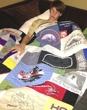 A young man sleeping under a T-shirt quilt on a couch Quilt by Too Cool T-shirt Quilts