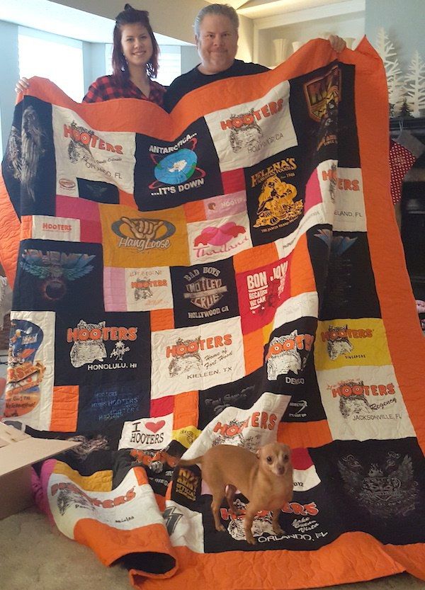 A daughter and father holding her T-shirt quilt at Christmas time.  by Too Cool T-shirt Quilts