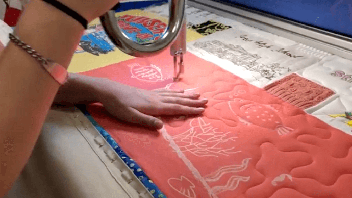 Milie long-arm quilting a T-shirt quilt.